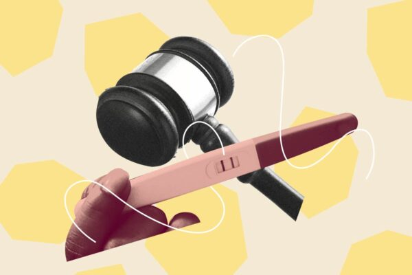 Pink hand holding a pregnancy test over a black and white gavel. Background is beige with light yellow geometric shapes