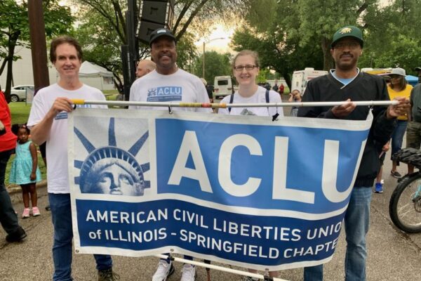 Group of people stand holding an ACLU of Illinois Springfield Chapter Banner