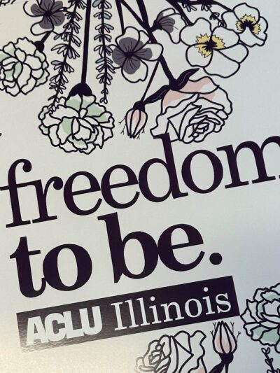 Photo of our Pride poster. Purple outlined flowers, purple text "freedom to be"