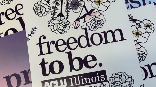 Photo of our Pride poster. Purple outlined flowers, purple text "freedom to be"