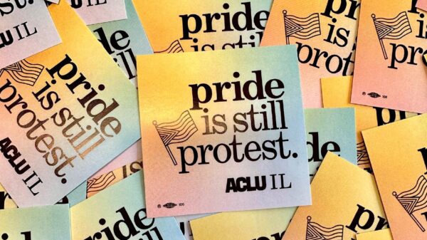 Photo of pile of stickers spread out. Stickers have a rainbow background and say "pride is still protest" with an outline of a Pride Flag