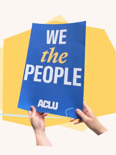 Hands holding blue sign that says "we the people' with yellow shapes behind it.