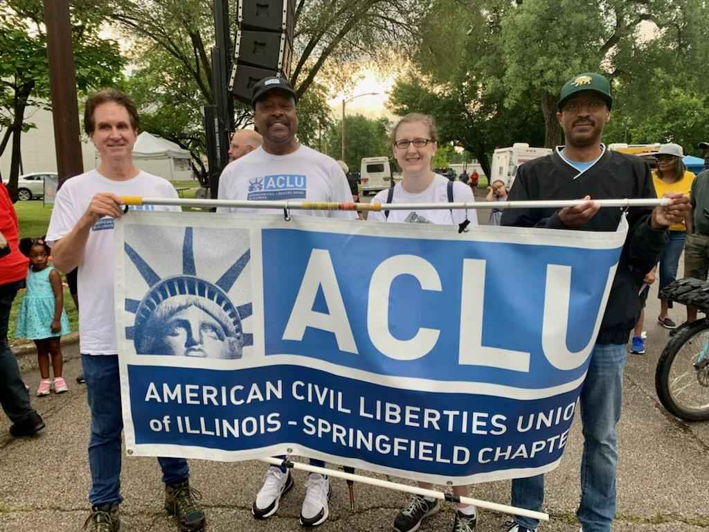 Group of people stand holding an ACLU of Illinois Springfield Chapter Banner